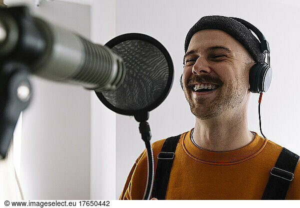 Happy freelancer with microphone singing at home studio