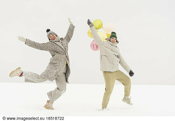 Happy friends dancing together in snow