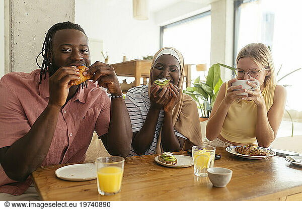 Happy friends having food and drinking coffee in cafe