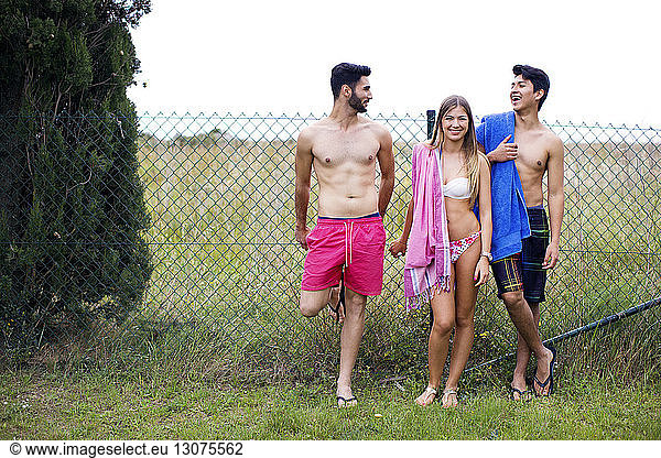 Happy friends in swimwear standing at yard