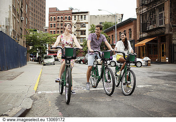 Happy friends riding bicycle on street
