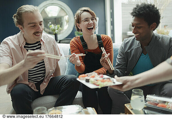 Happy friends sharing sushi in living room