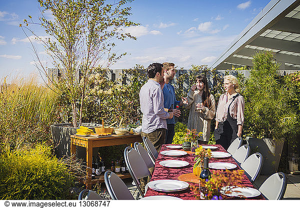 Happy friends standing by outdoor table during garden party