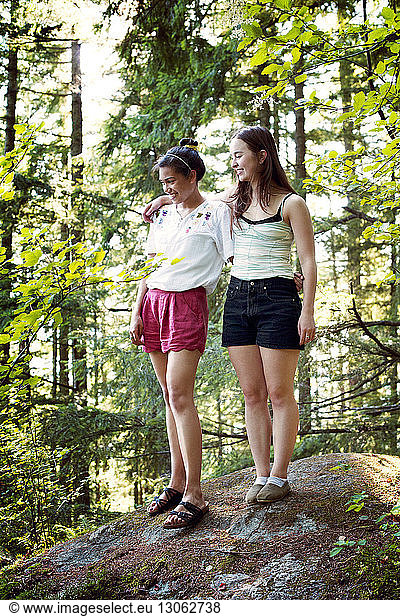 Happy friends standing in forest