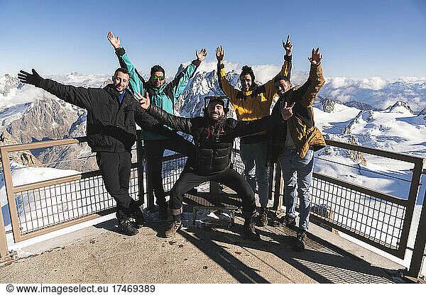 Happy friends with hands raised at viewpoint at Aiguille Du Midi  Mont Blanc  Chamonix  France