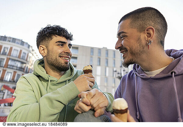 Happy gay couple eating ice cream at sidewalk cafe