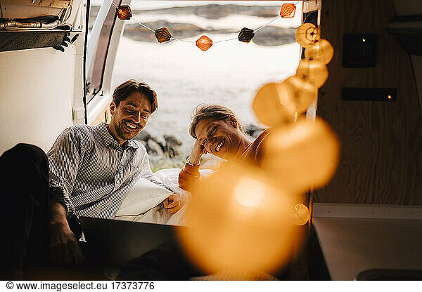 Happy gay couple using laptop in motor home during vacation