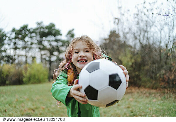 Happy girl giving soccer ball standing at park