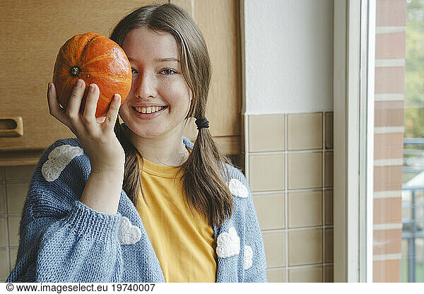 Happy girl holding pumpkin in hand at home