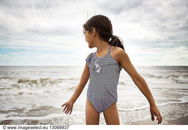Happy girl in swimwear standing against sea
