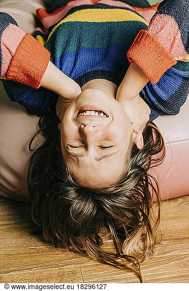 Happy girl lying upside down on bean bag