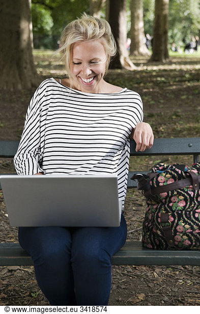 Happy girl on bench with computer