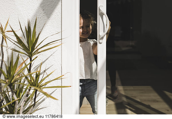 Happy girl opening glass door of house