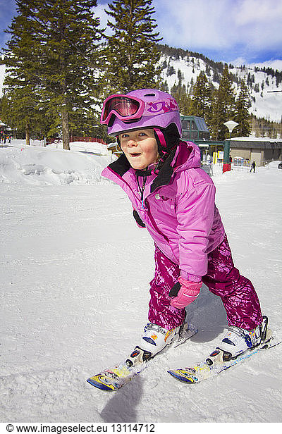 Happy girl skiing on snow covered field