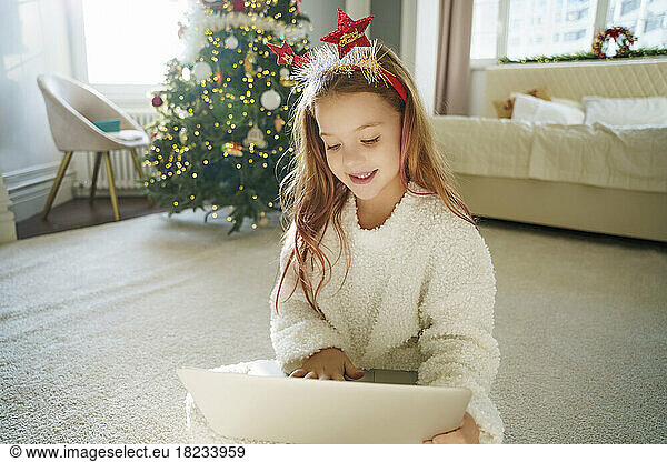 Happy girl using laptop sitting on carpet at home