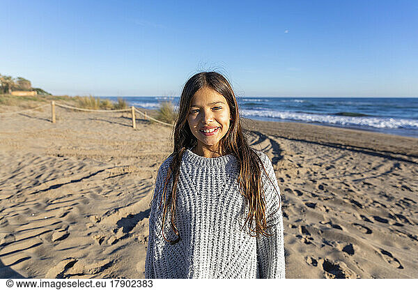 Happy girl wearing sweater standing at beach