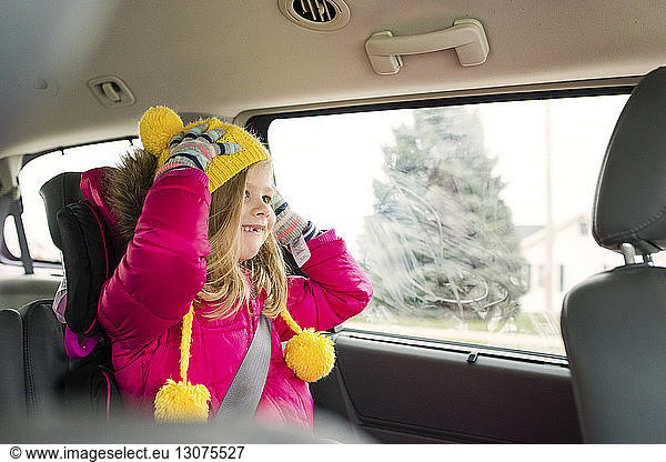 Happy girl wearing warm clothing traveling in car