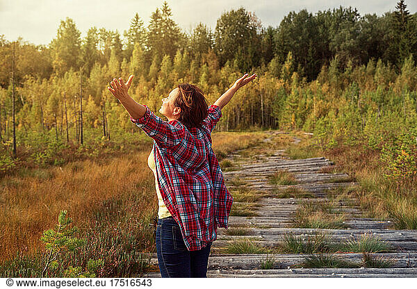 Happy girl with arms outstretched looks towards the sun