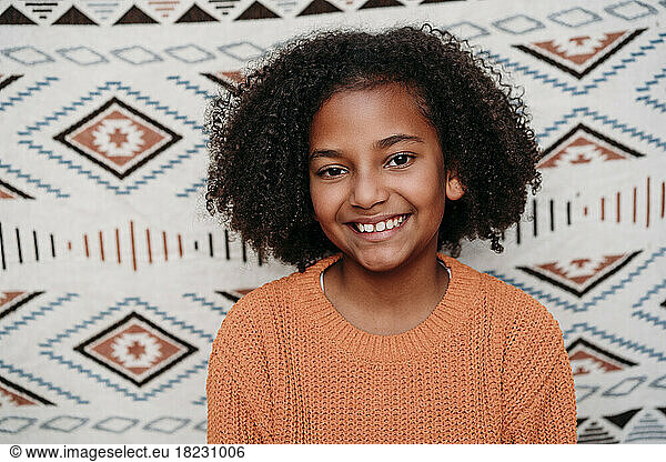 Happy girl with curly hair in front of patterned backdrop
