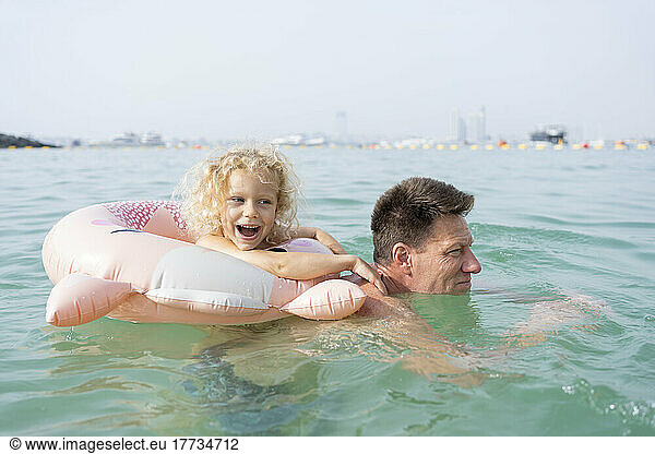 Happy girl with father swimming in sea
