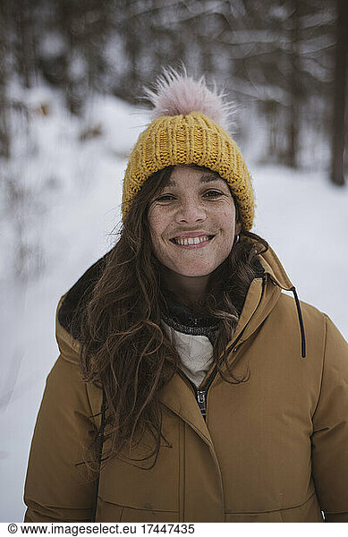 happy girl with freckles smiles in snow covered czech woods in winter