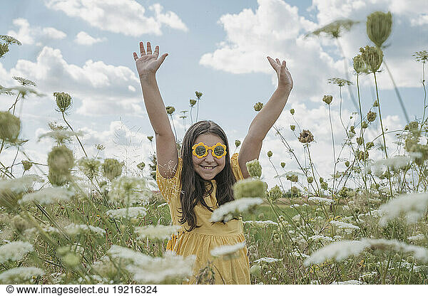 Happy girl with hands raised in flower field