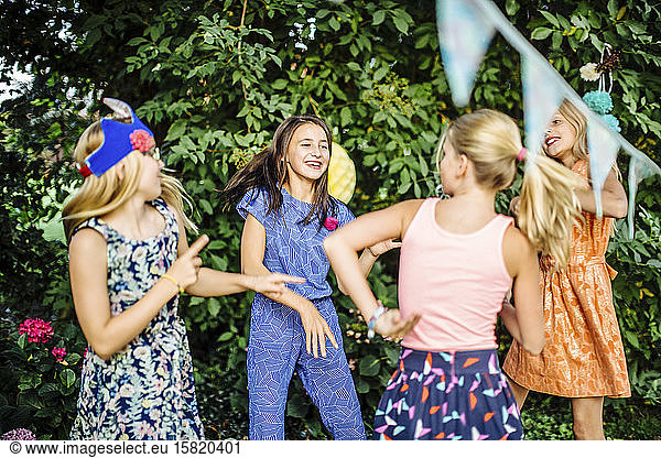Happy girls dancing on a birthday party outdoors