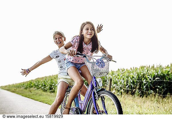 Happy girls riding bicycle on a country lane