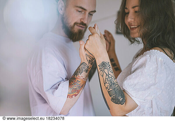 Happy hipster couple with tattoo on hands dancing together