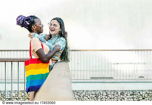 Happy homosexual multiracial girlfriends embracing on street