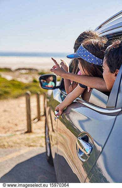 Happy kids leaning out car window at beach