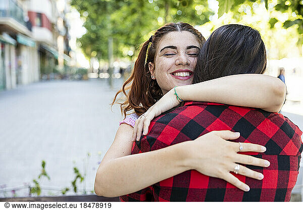 Happy lesbian couple hugging each other on footpath