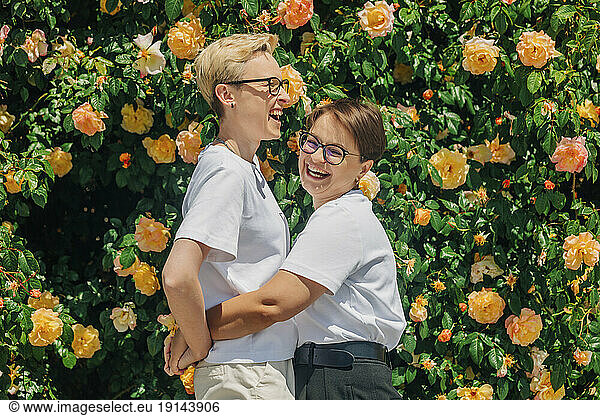 Happy lesbian couple in front of wall with roses