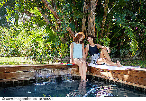 Happy lesbian couple relaxing at tropical summer swimming pool