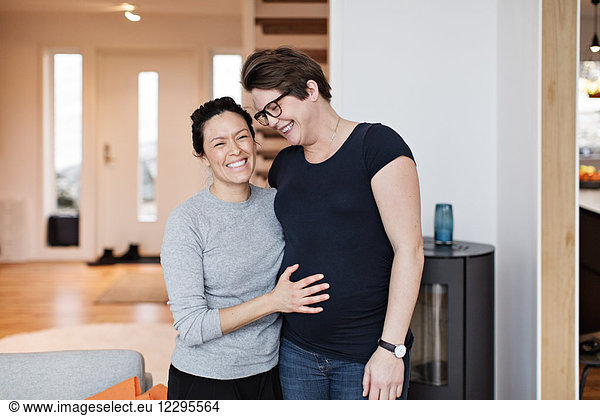 Happy lesbian couple standing in living room at home