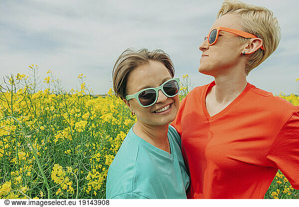 Happy lesbian couple wearing sunglasses at field