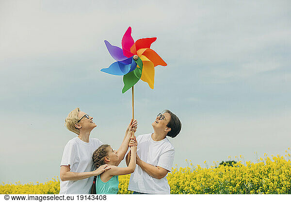 Happy lesbian mothers and daughter holding pinwheel toy at field