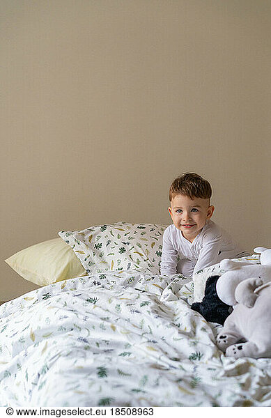 Happy little child boy in pajamas  in bed in the bedroom with to