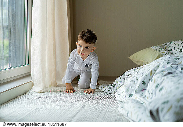Happy little child boy in pajamas  in bed in the bedroom with to