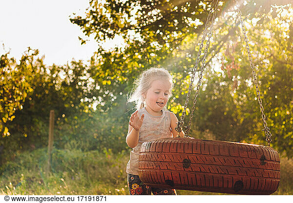 happy little girl in summer playing with a swing from the wheel