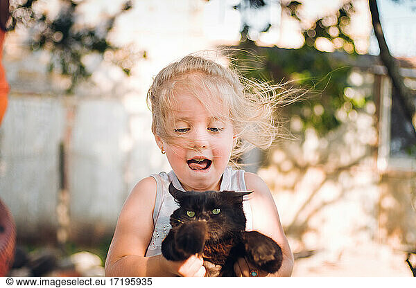happy little girl playing with kitten
