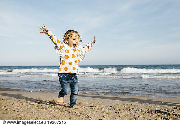 Happy little girl running barefoot on the beach