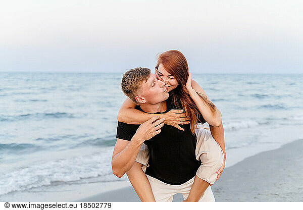 Happy lovers are having fun and fooling around near the sea on beach