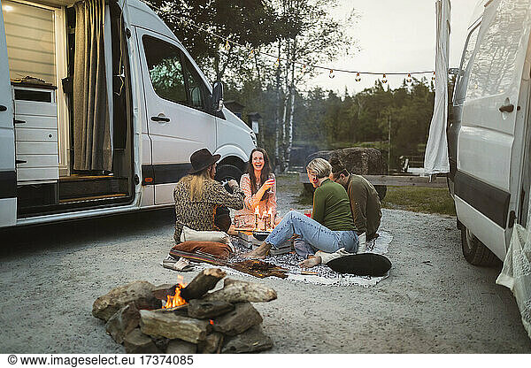 Happy male and female friends camping by motor home