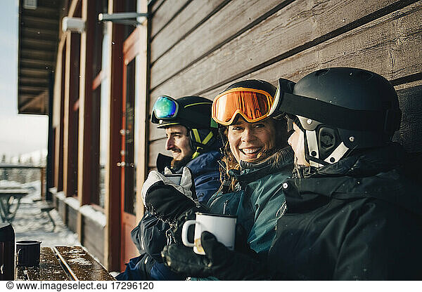 Happy male and female friends spending leisure time while having coffee at ski resort