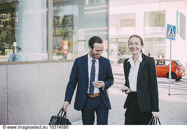 Happy male and female professionals in city