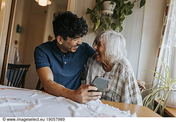Happy male caregiver with senior woman laughing at home