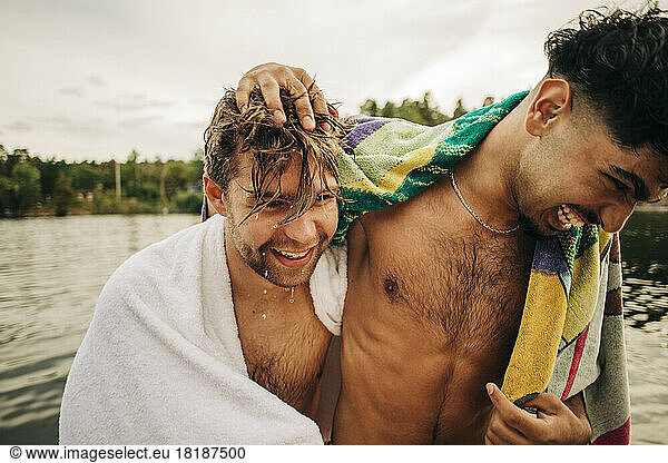 Happy male friends wearing towel enjoying during vacation