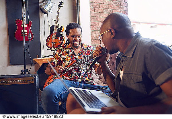 Happy male musicians practicing in recording studio