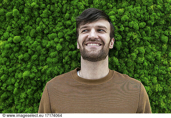 Happy male professional looking away against green backdrop